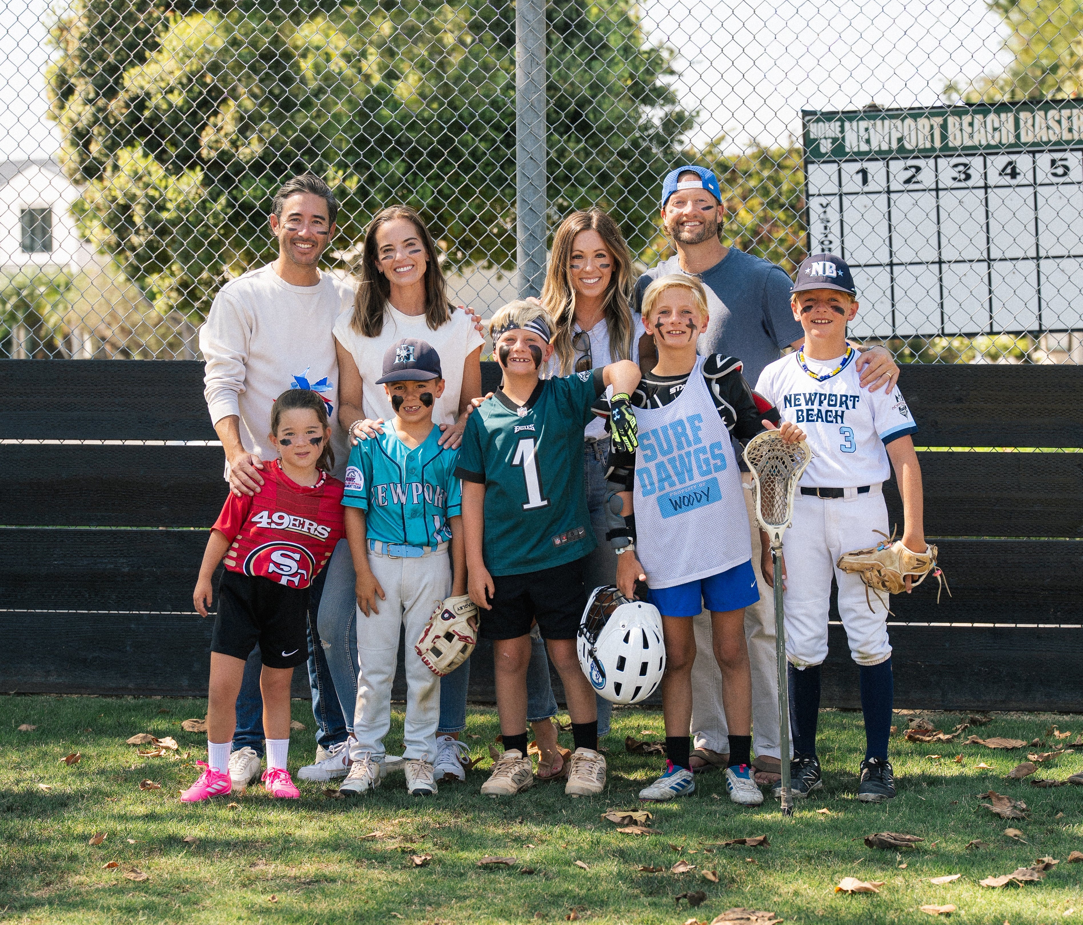 Two families of the MUGZ founders, Hunter and Marc. Everyone is wearing eye black and the kids are wearing sports uniforms.