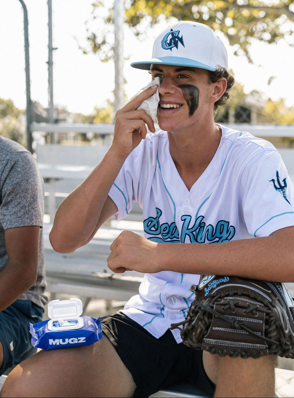 A high school baseball player wipes off his eye black with MUGZ Game Face Wipes.